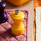 Salzmühle in safrangelb und Aubergine von Peugeot auf einem rosa Topflappen