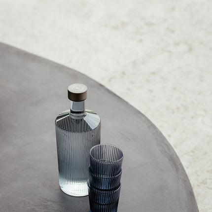 Paveau Glasflasche mit Wasser und farbigen Trinkgläsern